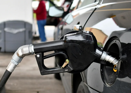 Black car being fueled with gas at a fuel station.